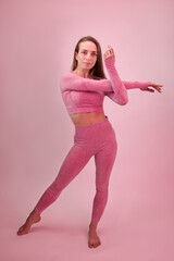 A dancer demonstrates dance warm-up movements in the style of modern dance on a pink background.