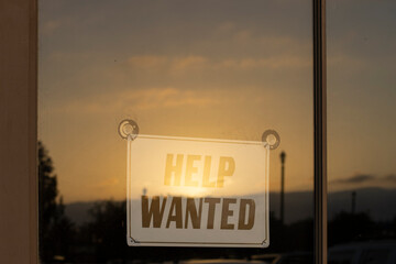 Help Wanted signage in the storefront window during sunset. America's labor shortage, labor costs,...