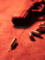 Hand gun with ammunition on dark background. 9 mm pistol military weapon and pile of bullets ammo at the metal table.