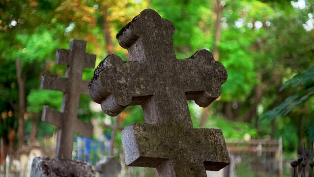 ancient stone cross covered in moss stands in a cemetery. mystical graveyard is filled with numerous graves, especially at sunrise and sunset.
