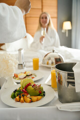 Man and woman in bathrobes celebrating in hotel room