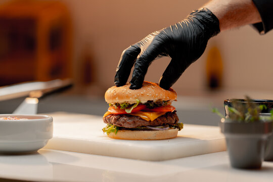 professional kitchen in a hotel restaurant, close-up of a chef pressing a burger with his hand