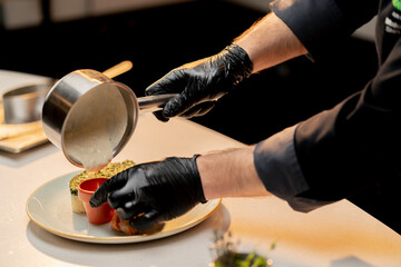 professional kitchen in a hotel restaurant close-up of a chef pouring sauce into a sauce pan
