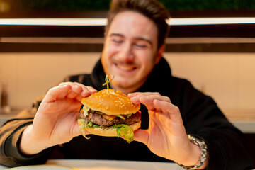 close-up man with enjoy biting delicious juicy cheeseburger in cafe restaurant junk food calories