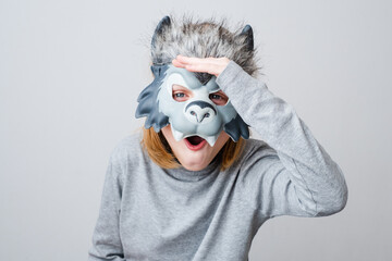 A surprised wolf looking at the camera, isolated on a gray background. Child wearing a wolf mask....