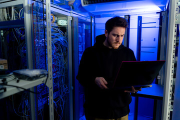 focused hacker in data center hacking software system vulnerable cyber security server room...