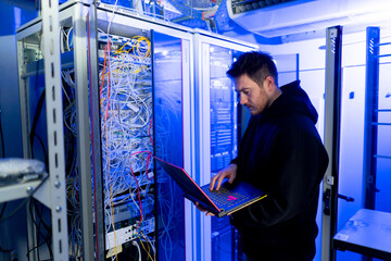 focused hacker in data center hacking software system vulnerable cyber security server room...