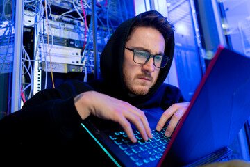 concentrated hooded hacker in data center hacking software system vulnerable cyber security server...