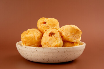 Brazilian cheese bread inside a white handmade bowl in a red clean background in front view