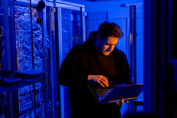 focused hacker in data center hacking software system vulnerable cyber security server room...
