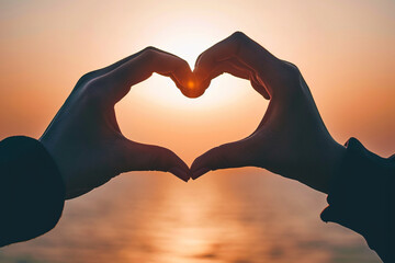 Two hands forming a heart shape against a tranquil sunset over the ocean