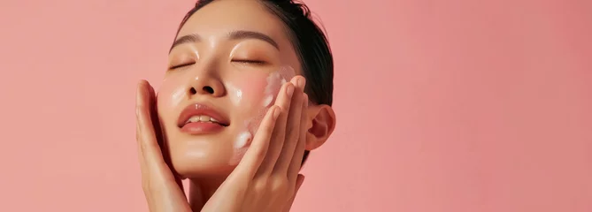 Fotobehang refreshing skincare regime with woman enjoying facial product on rosy background with large  copy space   © Klay
