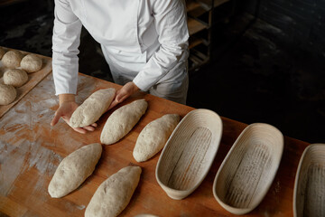 Baker hands preparing formed bread dough for proofing - obrazy, fototapety, plakaty