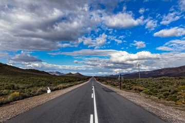 Carretera con un final infinito y bajo un cielo con nubes