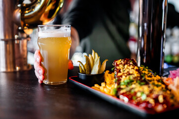 bartender's hand hold full glass of craft beer in a bar 