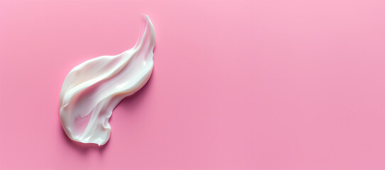 Smear of white creamy cosmetic product on a pink background. Beauty and skincare concept with a close-up view and space for text.