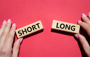Short vs Long symbol. Concept word Short vs Long on wooden blocks. Businessman hand. Beautiful red background. Business and Short vs Long concept. Copy space
