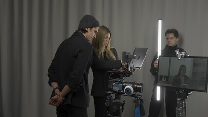 Female director, camera operator and lighting technician in the studio during filming. The lighting...
