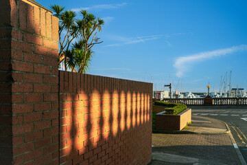 Golden sunshine shining through the shadows of a balustrade on a red brick wall in Ramsgate, Kent, UK.