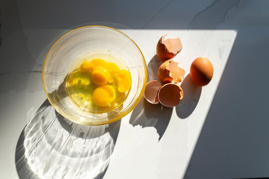 Cracked Eggs on Kitchen Counter with Yolks in Mixing Bowl