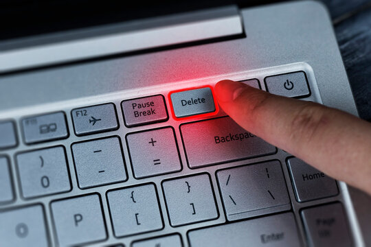 Pressing the delete button on the keyboard with your finger, the effect of red neon lighting. Removing problems, employee, negativity.