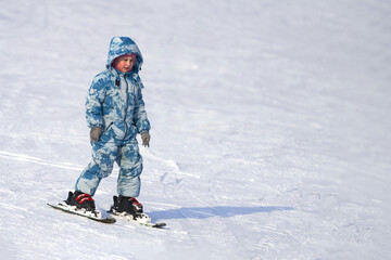 Fototapeta na wymiar A child learns to ski (balance) on alpine skis. Copy space.