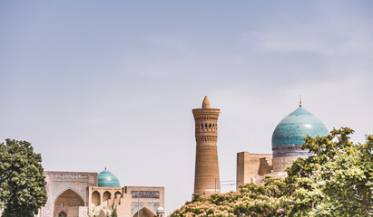 City panorama from the park at the mausoleum of the madrasah and the Kalon Minaret in the ancient city of Bukhara in Uzbekistan on a warm summer sunny day