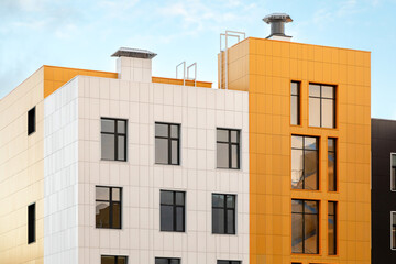 White yellow modern ventilated facade with windows. Fragment of a new typical residential building...