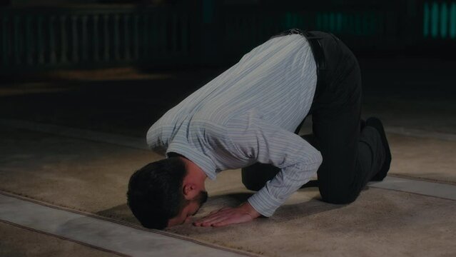 Sunni Muslim Man Going Down to Prostration in Islamic Prayer on a Mosque Carpet
