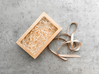 Empty kraft paper gift box on gray background and ribbon for wrapping, top view, holiday gift, Mother's Day, birthday, Valentine's Day, March 8 