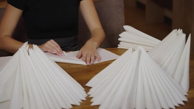 apprentice folding white napkins in restaurant