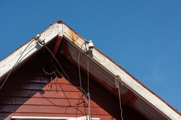 Power lines hanging from isplators on a roof.