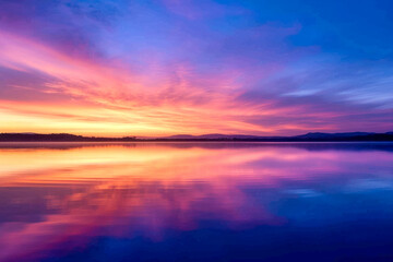 sunrise over a serene lake, with vibrant colors painting the sky