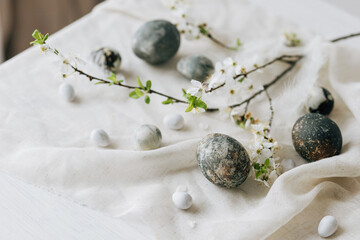 Stylish Easter eggs and spring flowers on rustic table. Happy Easter! Natural dye marble eggs and...