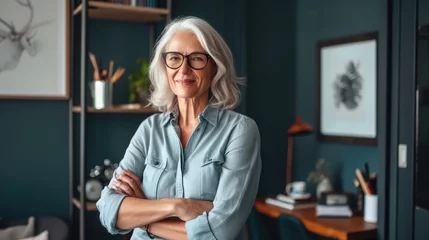 Fotobehang Smiling confident stylish mature middle aged woman standing at home office. Old senior businesswoman, lady executive business leader manager looking at camera arms crossed, portrait. © buraratn