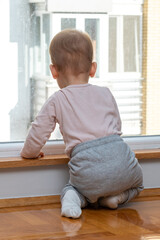 Baby gazes longingly through window, eager for an outdoor adventure. Concept of longing and childhood curiosity
