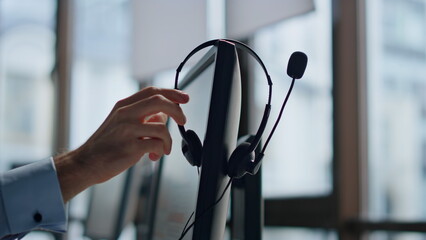 Closeup hand taking headset at call center. Technical support equipment hanging - obrazy, fototapety, plakaty