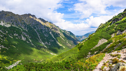 Fototapeta na wymiar Polish Tatra Mountains, high mountain hiking trail leading to mountain peaks, mountain landscape with valleys and slopes, view on a sunny summer day.