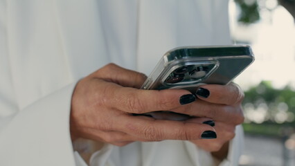 Business woman hands messaging telephone in city park close up. Girl typing sms.