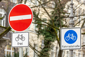 Bicycle street in Berlin with two traffic signs: "No passage, bicycles free" and "Bicycle street", each with a bicycle symbol. Old buildings in the background