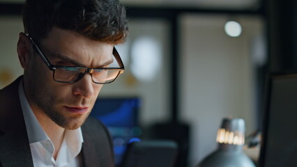 Late businessman using smartphone in office closeup. Focused man trader checking