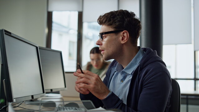 Focused programmer checking code at desk. It guy professional solving problem