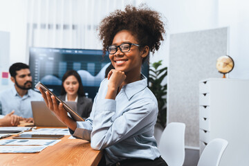 Happy young african businesswoman wearing glasses portrait with group of office worker on meeting with screen display business dashboard in background. Confident office lady at team meeting. Concord - Powered by Adobe