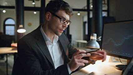 Finance broker working late in lamp light. Serious businessman check computer