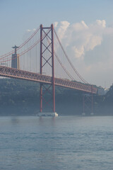Red bridge 25 de Abril Bridge and statue of Cristo Rei during a slightly misty day, Lisbon, Portugal