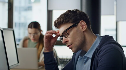 It developer overwork office closeup. Exhausted man project manager rubbing eyes