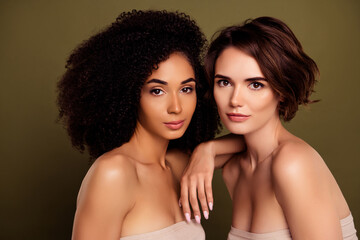 Portrait of two self confident gorgeous ladies enjoying feminine atmosphere isolated on khaki color background