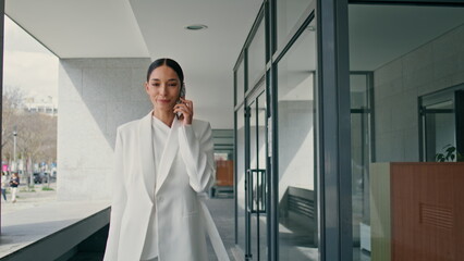 Fototapeta premium Young female director calling walking on business center close up. Lady talking 