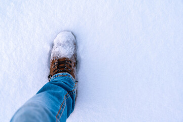 Warmer Winterschuh tritt in einer frische Schneedecke mit Textfreiraum