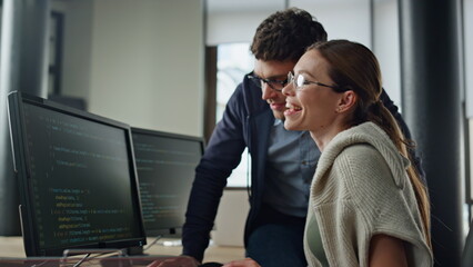 Smiling it intern discussing software code with supervisor. Friendly team work